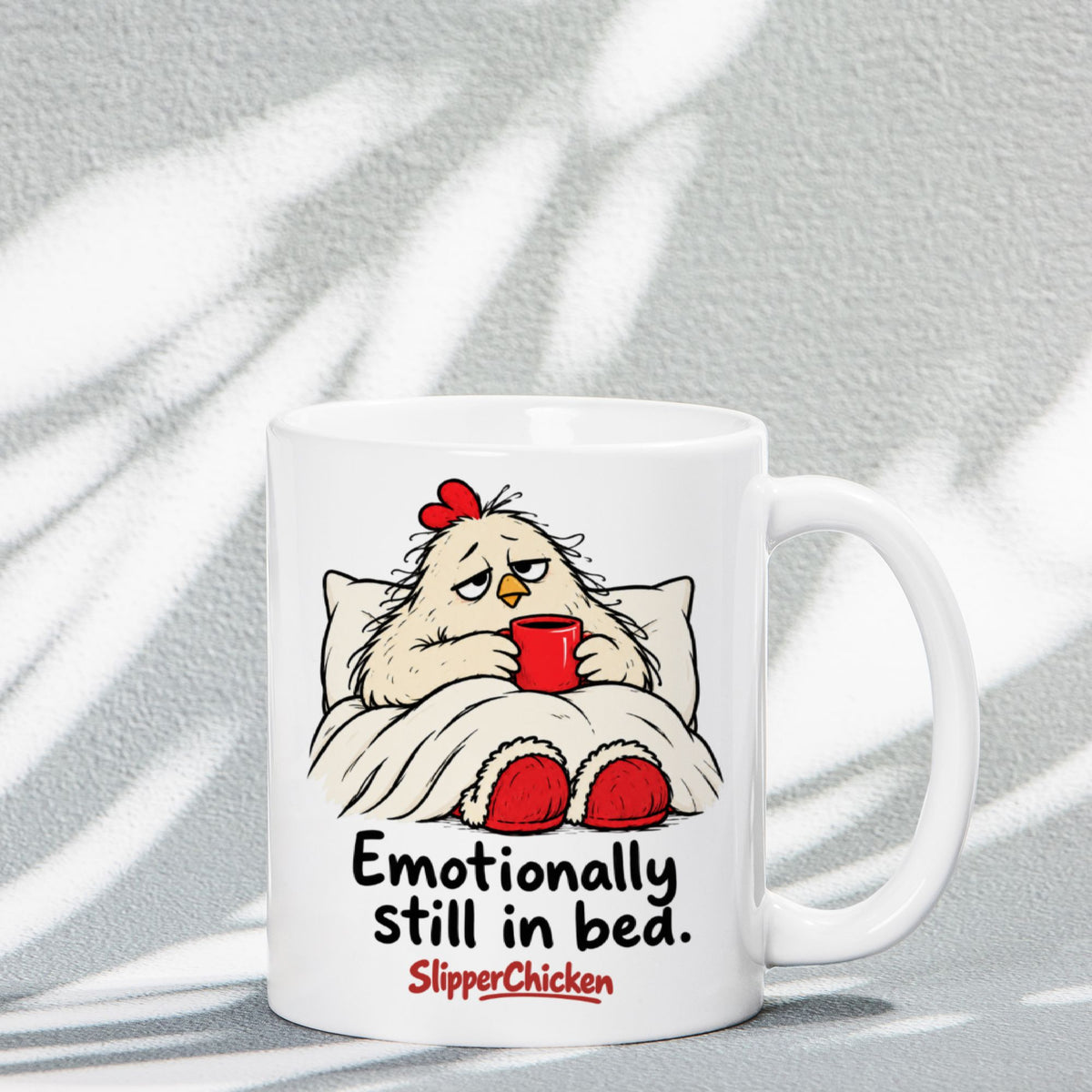 White Sleepy Mug with a chicken tucked into bed, Emotionally still in bed quote, and red SlipperChicken logo