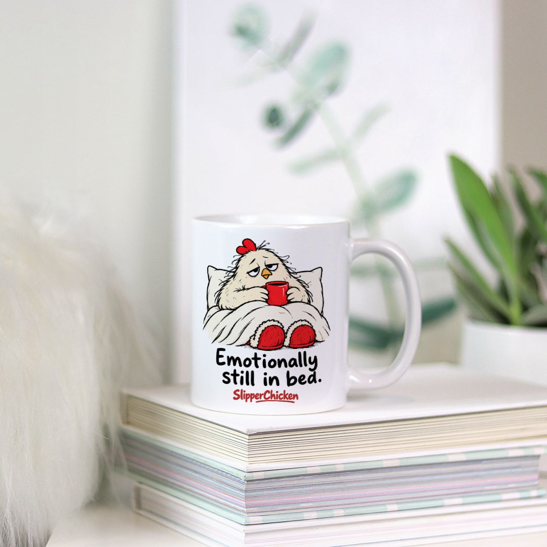 White Sleepy Mug with a chicken tucked into bed, Emotionally still in bed quote, and red SlipperChicken logo