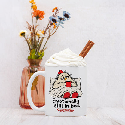 White Sleepy Mug with a chicken tucked into bed, Emotionally still in bed quote, and red SlipperChicken logo