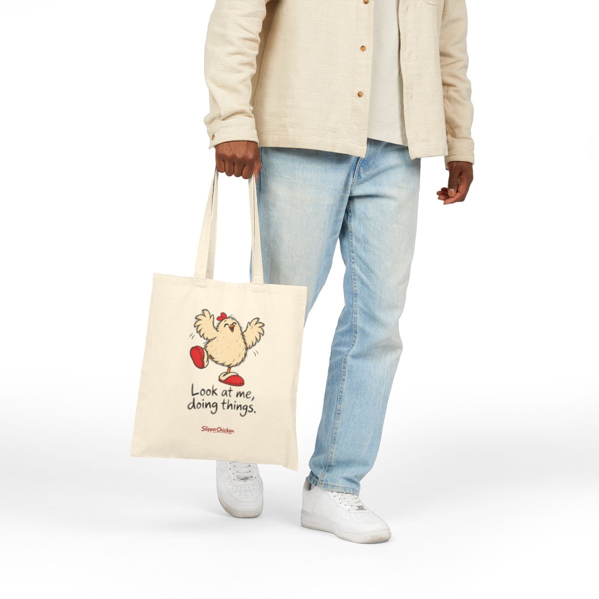 Native Printify mockup of the natural 15 × 16-inch Delighted Tote carried by hand, showing Look at me, doing things. at the saved print proportions.