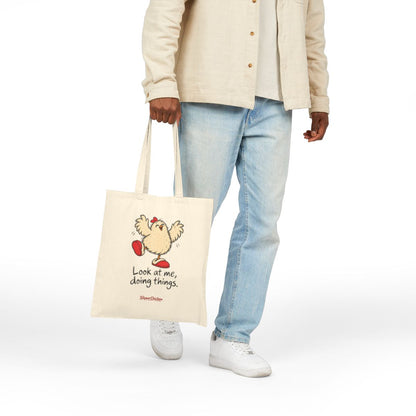 Native Printify mockup of the natural 15 × 16-inch Delighted Tote carried by hand, showing Look at me, doing things. at the saved print proportions.